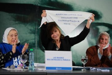 Florencia Saintout en el medio de la imagen mostrando el pañuelo blanco de las Madres de Plaza de Mayo, a su izquierda aplaudiendo, Hebe de Bonafini y a su derecha otra Madre de Plaza de Mayo