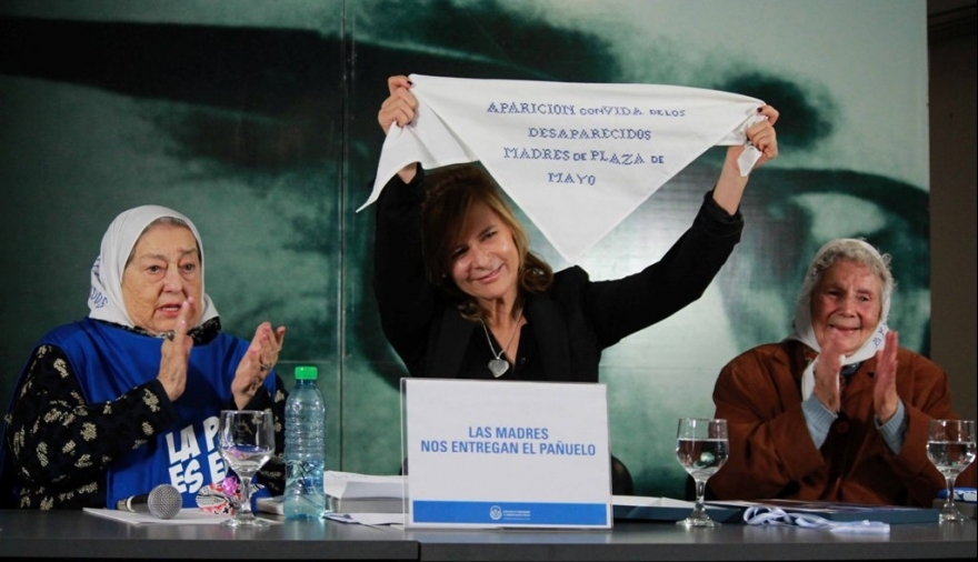 Florencia Saintout en el medio de la imagen mostrando el pañuelo blanco de las Madres de Plaza de Mayo, a su izquierda aplaudiendo, Hebe de Bonafini y a su derecha otra Madre de Plaza de Mayo