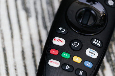 plano detalle a un control remoto en la que se ven los botones con el "logo de netflix", "logo prime video" y el de "movies"